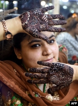 Perempuan Pakistan menunjukkan tangannya yang didekorasi henna untuk menyambut Idul Fitri.