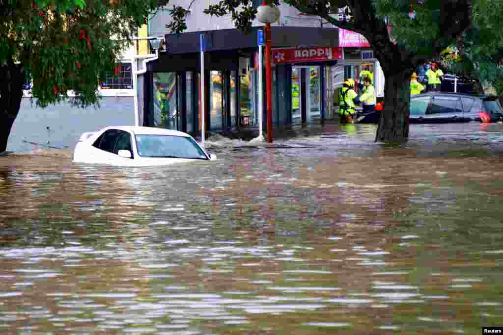 Rescue workers assist stranded people from floodwaters in the Auckland suburb of New Lynn in New Zealand.