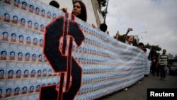 FILE - Demonstrators hold a banner made from three thousand two-bolivar-bills, that is equivalent approximately to $1 according to the black market exchange rate, in Caracas, Venezuela, June 10, 2017. 