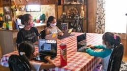 The Begaye sisters do their schoolwork at their home in Blue Gap, Ariz., on Sept. 24, 2020. (Megan Marples/Cronkite News via AP)