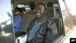 Uganda's Forum for Democratic Change leader Kizza Besigye smiles in a police van after he was arrested and charged for marching in a fourth round of protests against high prices, in the capital Kampala, April 21, 2011