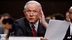 Attorney General Jeff Sessions reads from a statute about his recusal while testifying on Capitol Hill in Washington, June 13, 2017, before a Senate intelligence committee hearing. 
