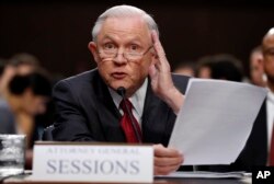 Attorney General Jeff Sessions reads from a statute about his recusal while testifying on Capitol Hill in Washington, June 13, 2017, before a Senate Intelligence Committee hearing.