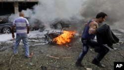 A Lebanese man runs in front of a burned car, at the scene where two explosions have struck near the Iranian Embassy killing many, in Beirut, Lebanon, Nov. 19, 2013. 