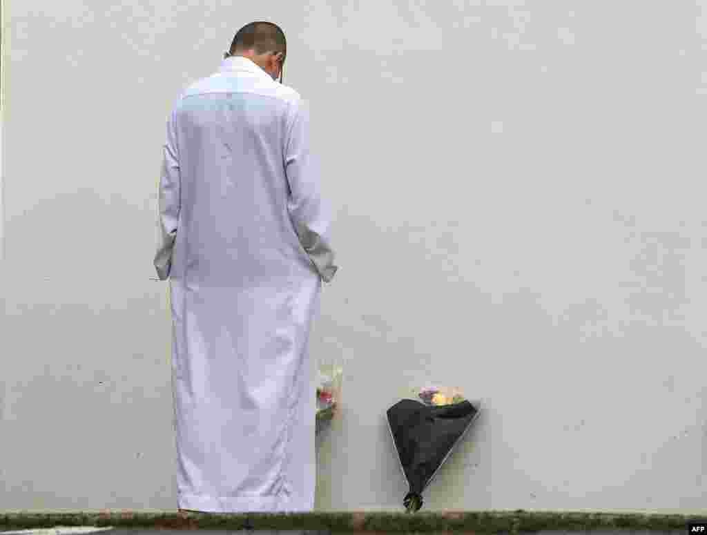 A man stands by flowers laid outside the mosque in Bayonne, France, a few days after an older man tried to set fire to the mosque and shot two men, aged 74 and 78, who came out to investigate.
