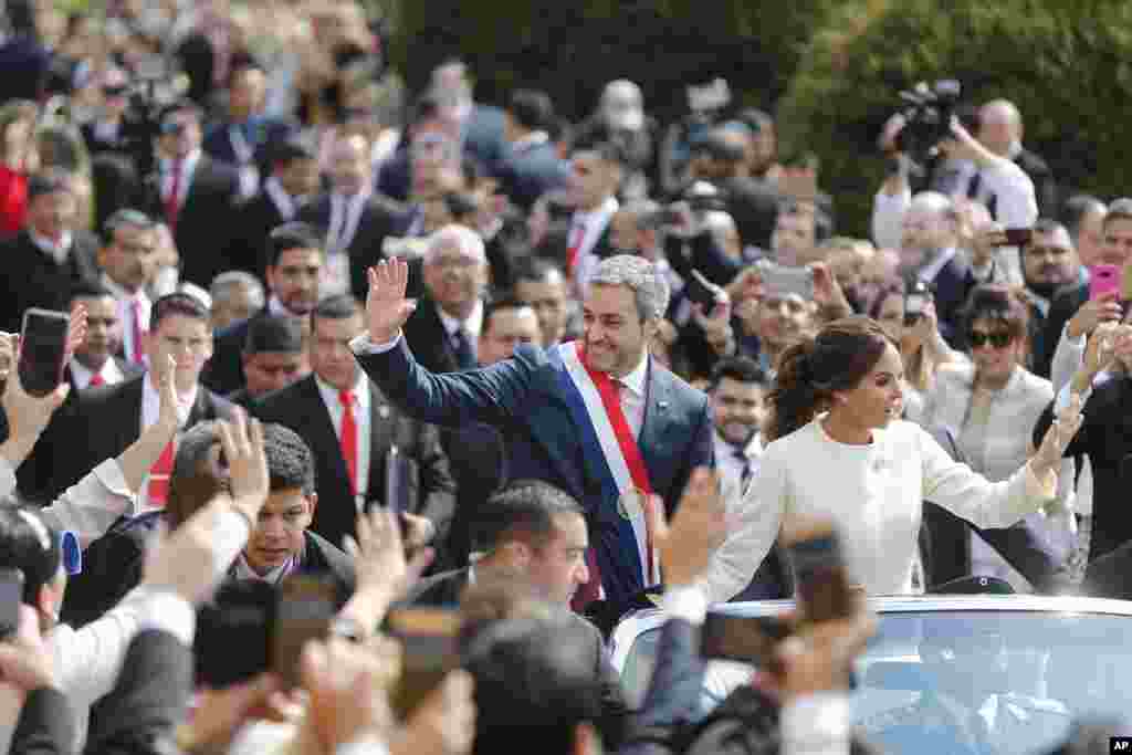 Paraguay&rsquo;ın yeni devlet başkanı Mario Abdo Benitez, göreve resmen başlamasını izleyen geçit töreninde eşi Silvana Lopez&rsquo;le birlikte üstü açık resmi araçtan halkı selamlıyor.