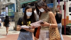 香港大學學生會成員（左）9月5日中午在銅鑼灣派發傳單，向市民講解杯葛全民檢測。 (美國之音 湯惠芸拍攝)