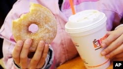 Ảnh tư liệu - Một bé gái cầm bánh và thức uống ở New York, ngày 14 tháng 2 năm 2013. Một nghiên cứu mới cho thấy hơn một nửa lượng calories tiêu thụ trong chế độ ăn uống trung bình của người Mỹ là từ thực phẩm chế biến sẵn, bao gồm thức uống có đường.