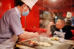 Kyuta Kumagai, 10, eats steak, which his father bought him as a reward after training, at 'Chime', a restaurant in Tokyo, Japan, August 21, 2020. On an average day, Kyuta will consume 2,700 to 4,000 calories. (REUTERS/Kim Kyung-Hoon)