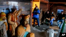 A medical worker and people waiting for COVID-19 vaccinations stand next to a nativity scene at the Christmas market in Offenbach, Germany, Nov. 24, 2021. The Christmas booth was turned into a temporary vaccination center, where people queued for hours.