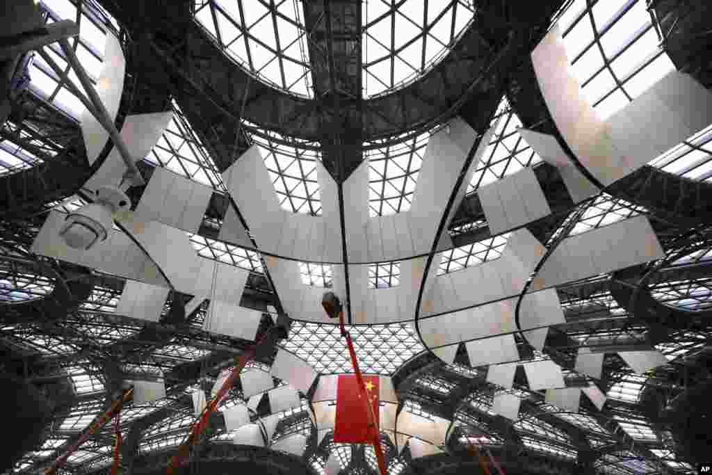 Building crews use basket cranes to work on an elevated area inside the terminal building at Beijing Daxing International Airport in Beijing, China.