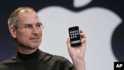 In this Jan. 9, 2007 file photo, Apple CEO Steve Jobs holds up an Apple iPhone at the MacWorld Conference in San Francisco. Apple Inc. on