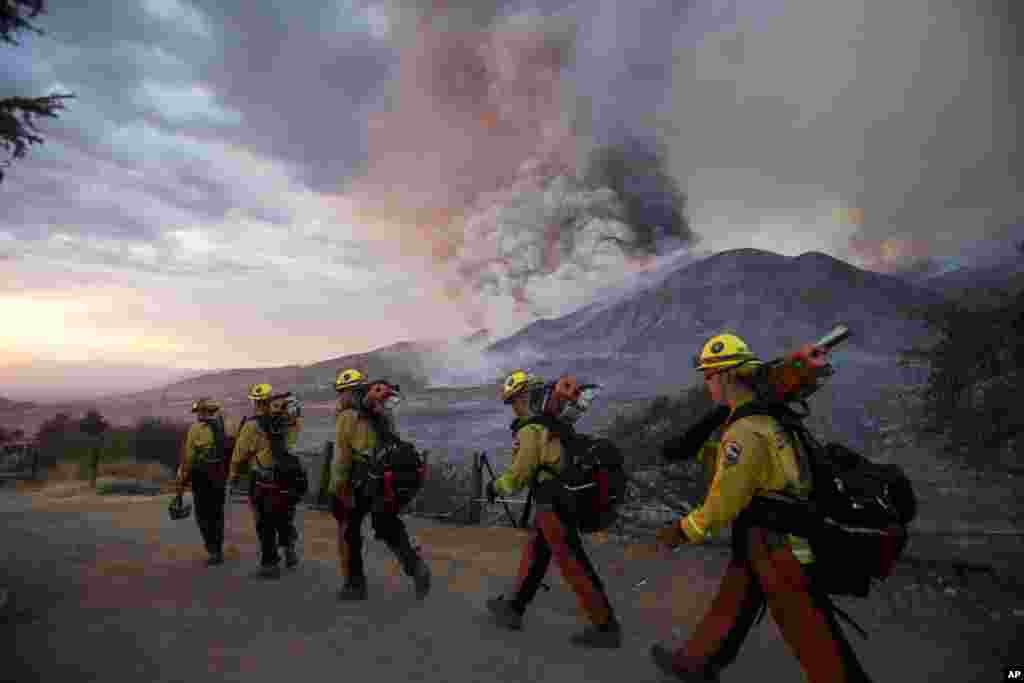 Firefighters walk in line during a wildfire in Yucaipa, California.&nbsp;Three fast-spreading wildfires sent people fleeing with one trapping campers at a reservoir in the Sierra National Forest, as a brutal heat wave pushed temperatures into triple digits in many parts of state.