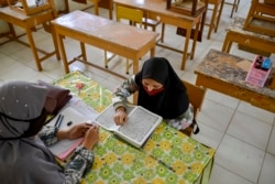 Seorang pelajar mengenakan masker untuk mencegah penularan virus corona, sedang ujian membaca Alquran di Banda Aceh, 10 Juni 2020. (Foto: AFP)