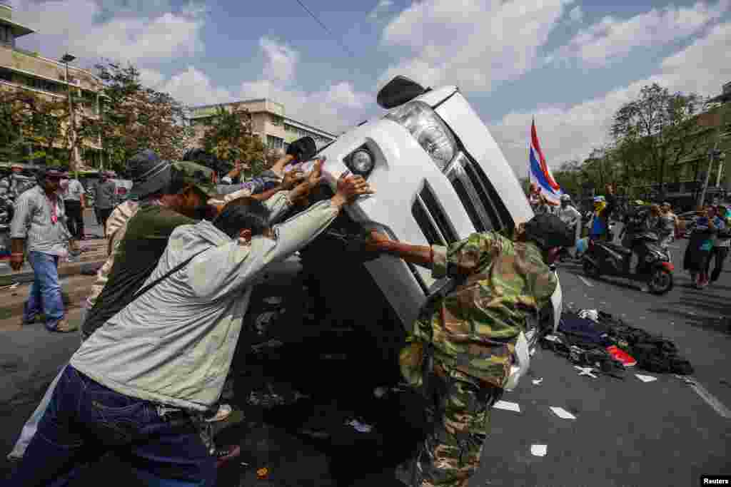 Anti-government protesters lift a police car after clashes with Thai riot police officers, near Government House, Bangkok Feb. 18, 2014.&nbsp; 