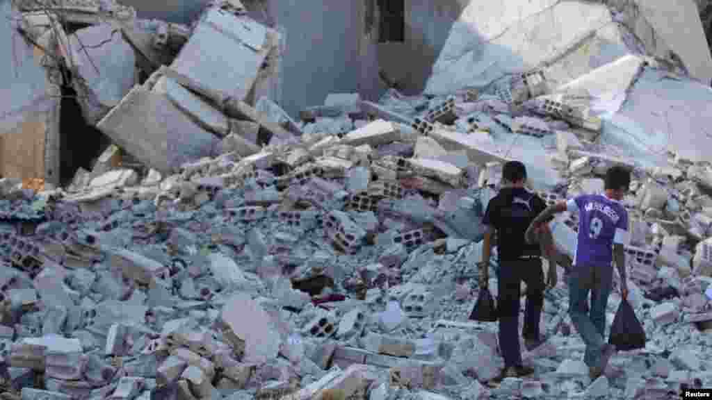 Boys walk on the rubble of damaged buildings in Duma neighborhood of Damascus, Sept. 23, 2013. 