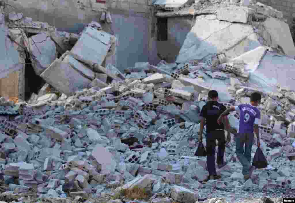 Boys walk on the rubble of damaged buildings in Duma neighborhood of Damascus, Sept. 23, 2013. 