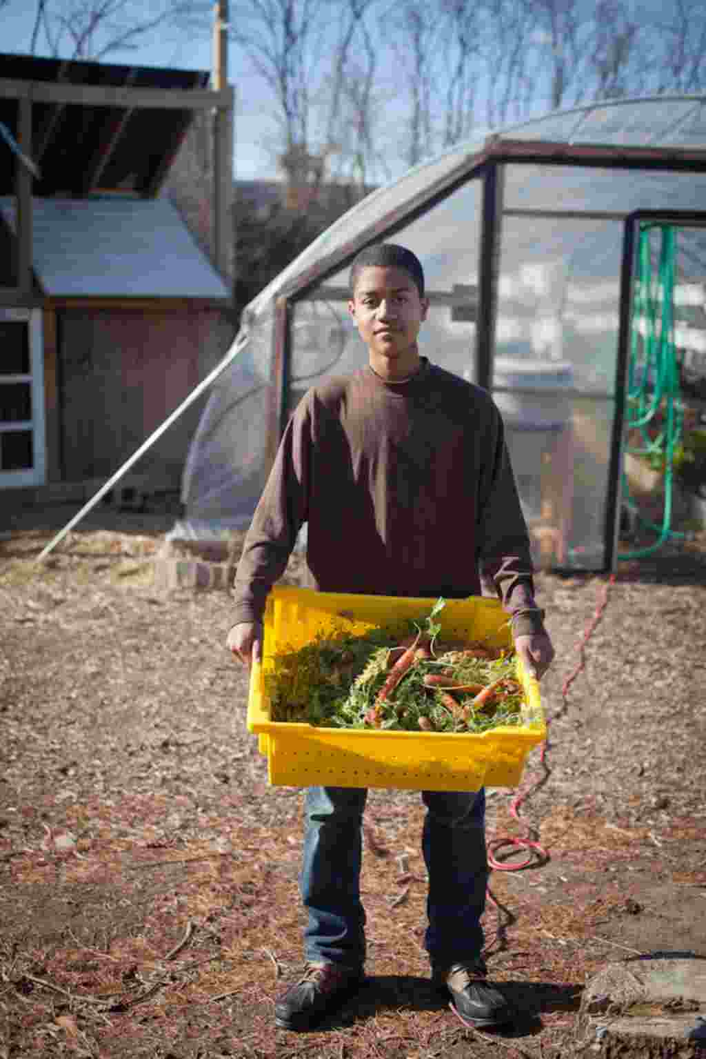 El voluntario John Clark muestra la cosecha de zanahorias de la granja.