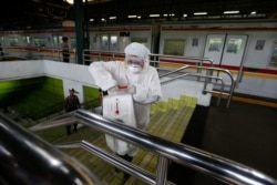 Seorang petugas medis mengenakan baju pelindung menyemprotkan cairan disinfektan di Stasiun Gambir setelah pemerintah mengonfirmasi kasus virus corona (Covid-19) di Jakarta, 12 Maret 2020. (Foto: Reuters)