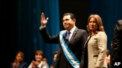 Guatemala’s new President Jimmy Morales greets the public as he holds hands with his wife, first lady Hilda Marroquin, after he was sworn-in at the National Theater in Guatemala City, Thursday, Jan. 14, 2016.