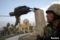 FILE - U.S. Marine Corp Assaultman Kirk Dalrymple watches as a statue of Iraq's President Saddam Hussein falls in central Baghdad, April 9, 2003.