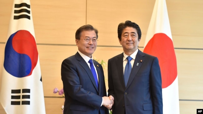 韩国总统文在寅在东京与日本首相安倍晋三握手（2018年5月9日）