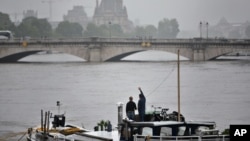 A man waves standing on a barge on the Seine river during floods, in Paris, June 5, 2016. Flooding in French capital is part of a weeklong deluge that has swamped large parts of Europe, killing at least 18 people in Germany, France, Romania and Belgium.