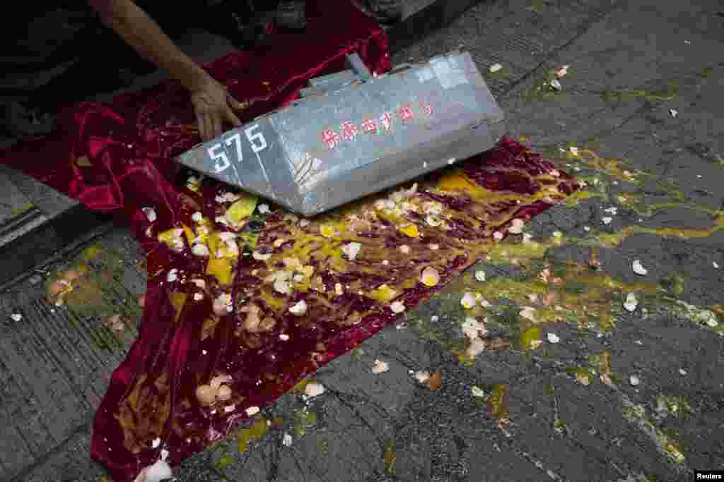 Pecahan telur &nbsp;di atas bendera dan model kapal angkatan laut China yang dilemparkan oleh para demonstran Vietnam anti-China di Hong Kong (19/5). (Reuters/Tyrone Siu)