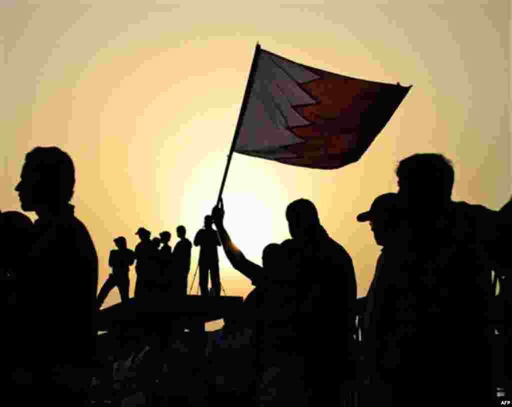 Anti-government protesters wave a Bahraini flag as the sun sets during an opposition march of tens of thousands Friday, Feb. 24, 2012, in Sehla, Bahrain, on the edge of the capital of Manama. Demonstrators called for freedom for political prisoners and de