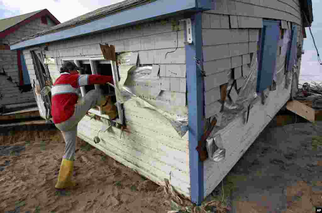 Christopher Hannafin, of South Kingstown, R.I., enters a friend's cottage through a window to salvage belongings from the structure destroyed by Superstorm Sandy, on Roy Carpenter's Beach, in the village of Matunuck, in South Kingstown, Oct. 30, 2012. 