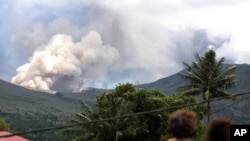 Residents look on as Mount Lokon spews volcanic ash during an eruption in Tomohon in Indonesia's North Sulawesi province, July 17, 2011