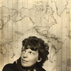 Amelia Earhart in front of a map of her proposed trip around he world