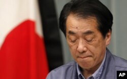 日本首相菅直人在记者会上，旁边是镶了黑边的日本国旗