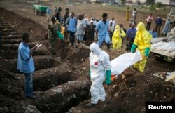Health workers carry the body of an Ebola victim for burial at a cemetery in Freetown, December 17, 2014.