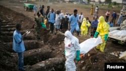 Des agents de santé portent le corps d'une victime Ebola pour l'enterrement dans un cimetière de Freetown (Sierra Leone), le 17 Décembre 2014