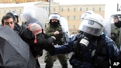 Riot police scuffle with a female protester as they try to open the avenue outside the Greek Parliament during a heavy rain in Athens, February 7, 2012.