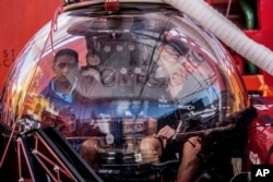 Seychelles President Danny Faure, left, sits inside a submersible on the deck of vessel Ocean Zephyr, off the coast of Desroches, in the outer islands of Seychelles, April 13, 2019.