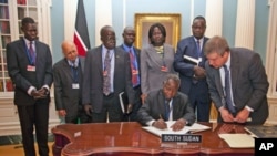 South Sudan's Minister of Finance and Economic Planning Kosti Manibe Ngai (L) signs the treaty to become IMF's newest member as US State Department Treaty Analyst Francis Holleran (R) looks on at the State Department, April 18, 2012 in Washington.
