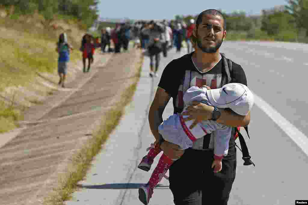 A Syrian migrant carries a baby as he walks towards the Greece border on a road near Edirne, Turkey.