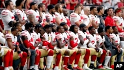 Members of the San Francisco 49ers kneel during the national anthem as others stand before the start of an NFL football game against the Arizona Cardinals, Oct. 1, 2017, in Glendale, Arizona.