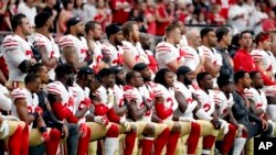 FILE - Members of the San Francisco 49ers kneel during the national anthem as others stand at an NFL game against the Arizona Cardinals, Oct. 1, 2017, in Glendale, Arizona.