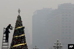 Workers install a Christmas tree on display outside a shopping mall in a heavy pollution haze in Beijing, Tuesday, Dec. 8, 2015.