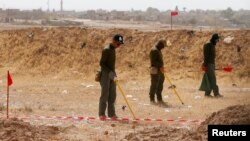 FILE - Mine clearers search for mines and explosive devices at Hammam al-Alil city, south of Mosul, Iraq, July 29, 2017. 