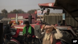Sonu Singh ties his turban while getting ready to join other farmers protesting against new farming laws they say will result in exploitation by corporations.