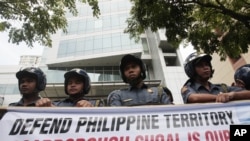 Policemen stand guard behind a protest banner outside the Chinese consulate in Manila's financial district of Makati, Philippines, May 11, 2012. 