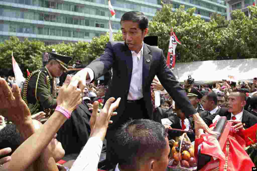 Presiden&nbsp;Joko Widodo di tengah kerumunan rakyat dalam parade jalanan menyusul pelantikannya di Jakarta (20/10).&nbsp;(AP/Achmad Ibrahim) 