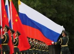 Pasukan kehormatan China mengibarkan bendera Rusia dalam upacara penyambutan bagi Presiden Rusia Vladimir Putin di Beijing (foto: dok).