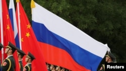 2018年6月8日在中國北京人民大會堂外，中國國家主席習近平為俄羅斯總統普京主持的歡迎儀式上，一名解放軍軍官在調整俄羅斯國旗。