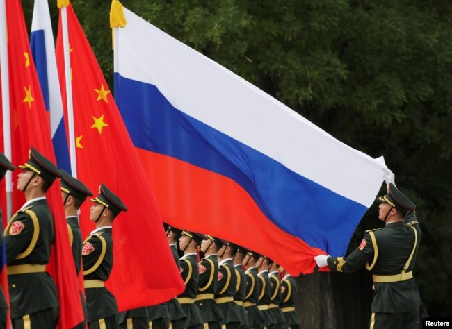 Pasukan kehormatan China mengibarkan bendera Rusia dalam upacara penyambutan bagi Presiden Rusia Vladimir Putin di Beijing (foto: dok).