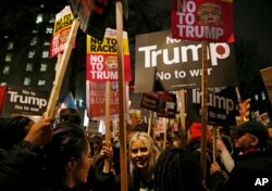 Demonstrators hold banners as they take part in a protest against U.S President Donald Trump's controversial travel ban on refugees and people from seven mainly-Muslim countries, outside Downing Street in London, Jan. 30, 2017.